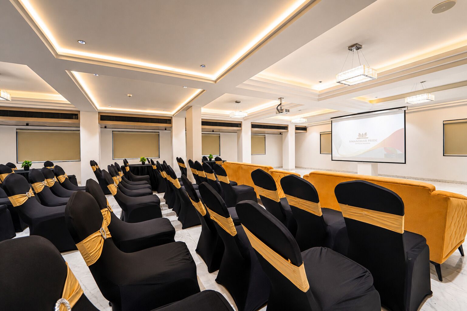 A conference room with rows of chairs, a podium, and a projector screen.