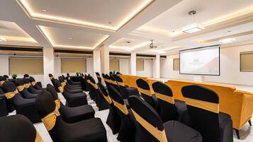A conference room with rows of chairs, a podium, and a projector screen.
