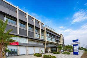 Un edificio moderno con varios pisos, balcones y cielo despejado.