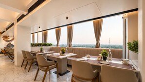 A modern dining area with a long table, chairs, and a view of the cityscape.