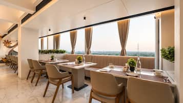 A modern dining area with a long table, chairs, and a view of the cityscape.