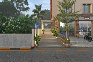 A hotel entrance with a modern design, a visible sign for Levi's store, and a motorcycle parked outside. - Aarambh by The Sky Imperial Jamnagar (Jamnagar bypass highway)