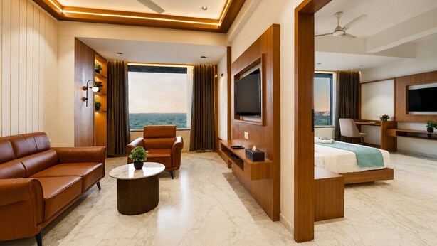 A modern hotel room with a sofa, armchair, TV, and a bed with a view.