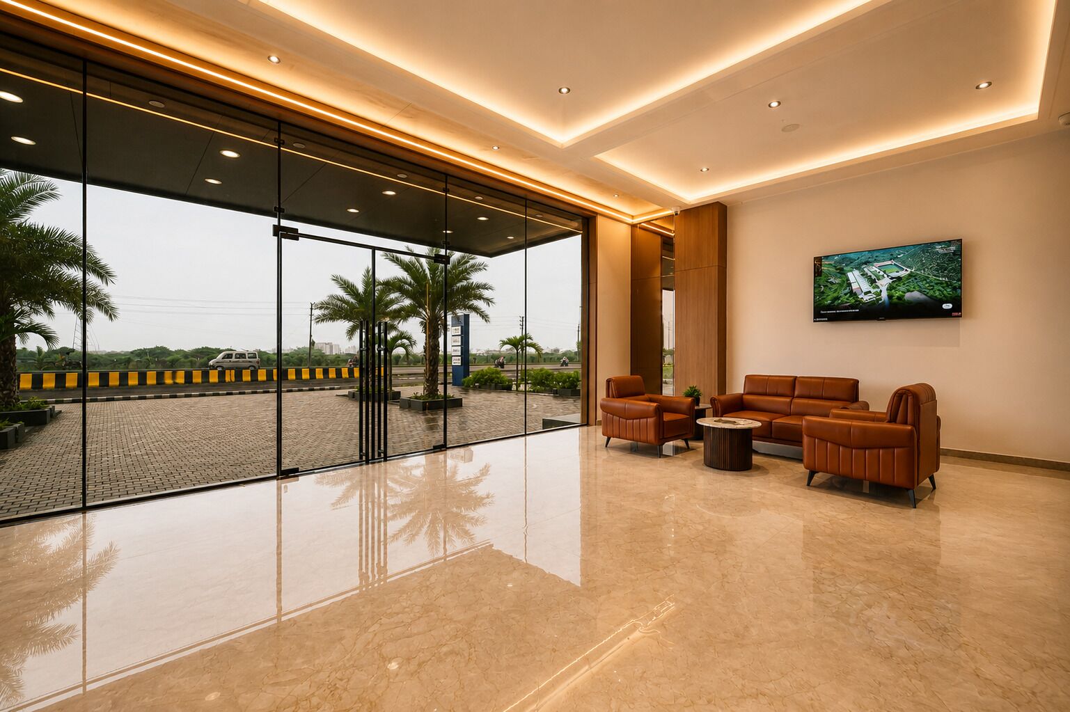 A modern lobby with a glass entrance, leather seating, and a mounted TV.