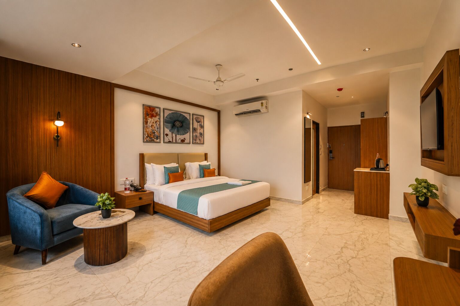 A modern hotel room with a bed, a sofa, a desk, and a television.