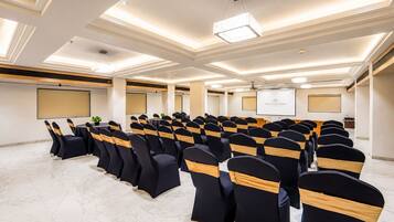 A conference room with rows of chairs, a podium, and a projector screen.