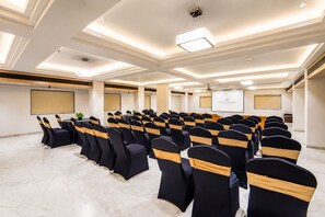 Un salón de conferencias con hileras de sillas, un atril y una pantalla para proyector.