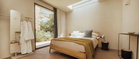 Un dormitorio con cama, mesita de noche, espejo y ventana.