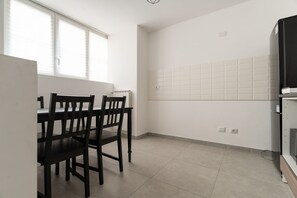 A kitchen with a dining table and chairs, a refrigerator, and a tiled backsplash. - A cozy 60 sqm apartment that sleeps up to 4 people, located on the semi-basement level of a building (accessible via stairs).The neighborhood is well-connected to the city center and major attractions by public transport; the Tolstoj stop on the M4 met (Milan)