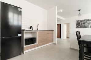A modern kitchen with a black refrigerator, a microwave, and a sink. There is a dining area with a table and chairs. - A cozy 60 sqm apartment that sleeps up to 4 people, located on the semi-basement level of a building (accessible via stairs).The neighborhood is well-connected to the city center and major attractions by public transport; the Tolstoj stop on the M4 met (Milan)