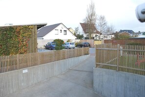 A residential street with houses, a wooden fence, and parked cars. - Vrbo Property (Büsum)
