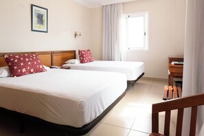 Una habitación de hotel con dos camas, un escritorio y una ventana con cortinas.