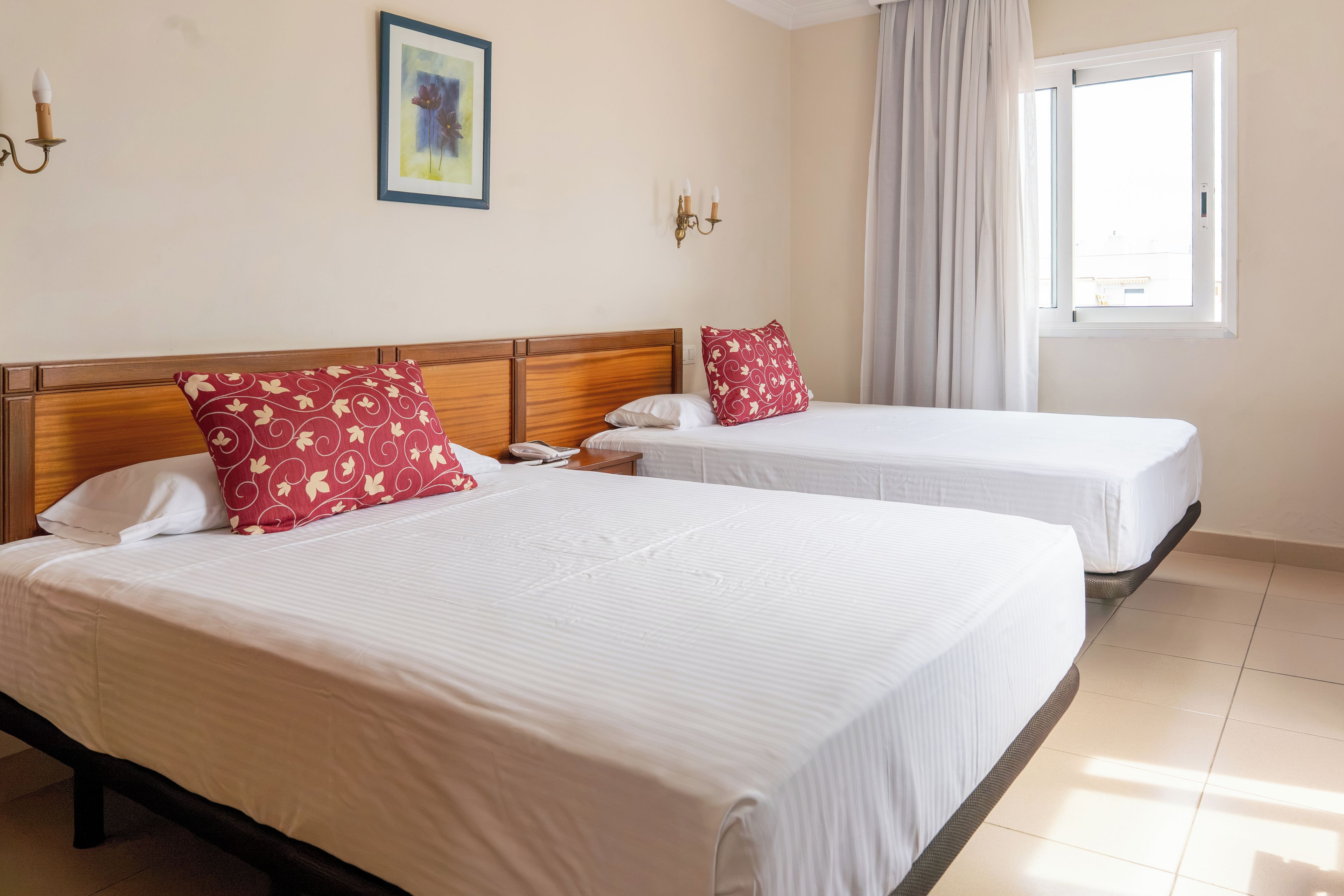 Una habitación de hotel con dos camas, un ventanal con cortinas y un cuadro colgado en la pared.