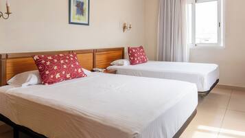 Una habitación de hotel con dos camas, un ventanal con cortinas y un cuadro colgado en la pared.