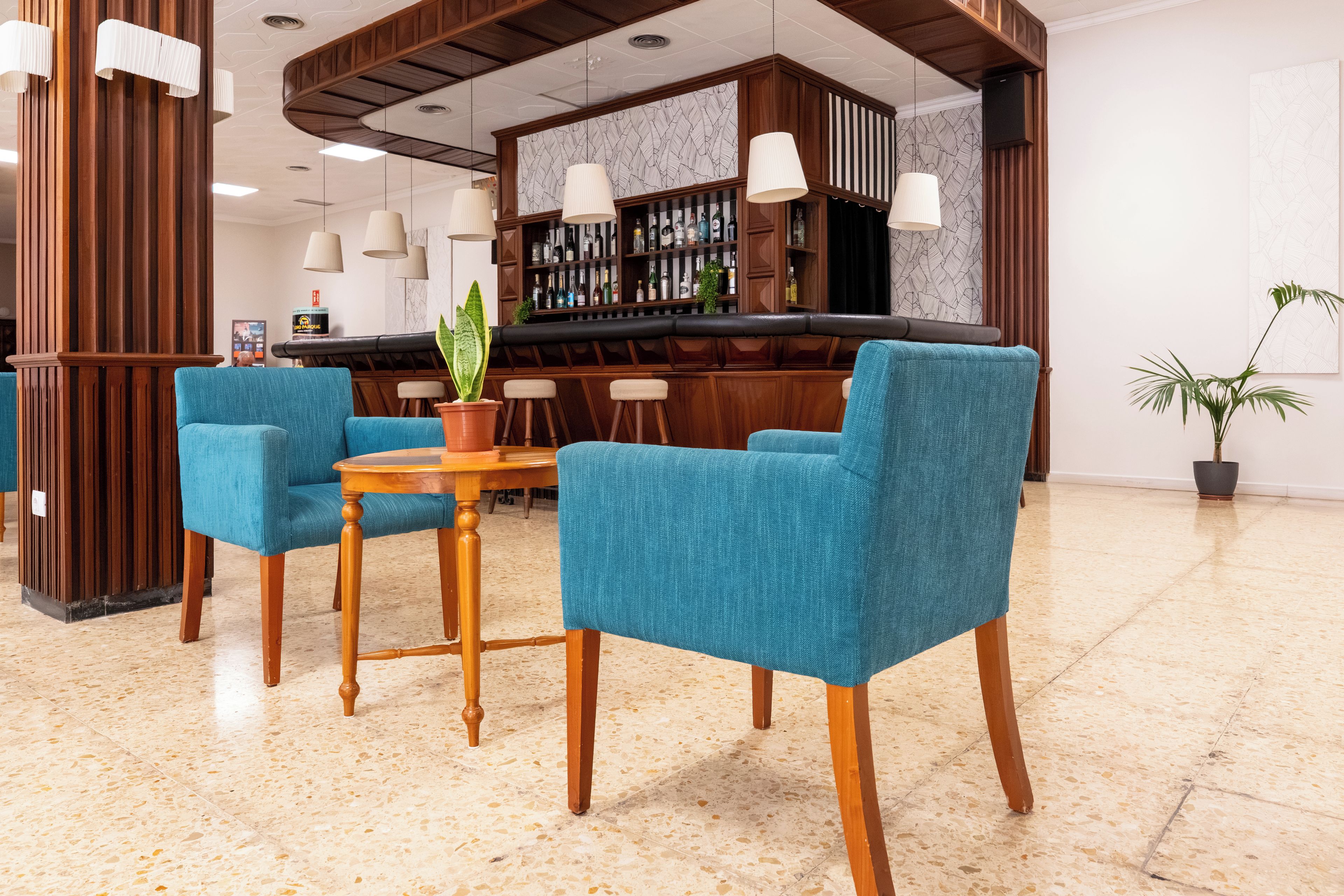 Zona de bar con mobiliario de madera y suelo de baldosas.