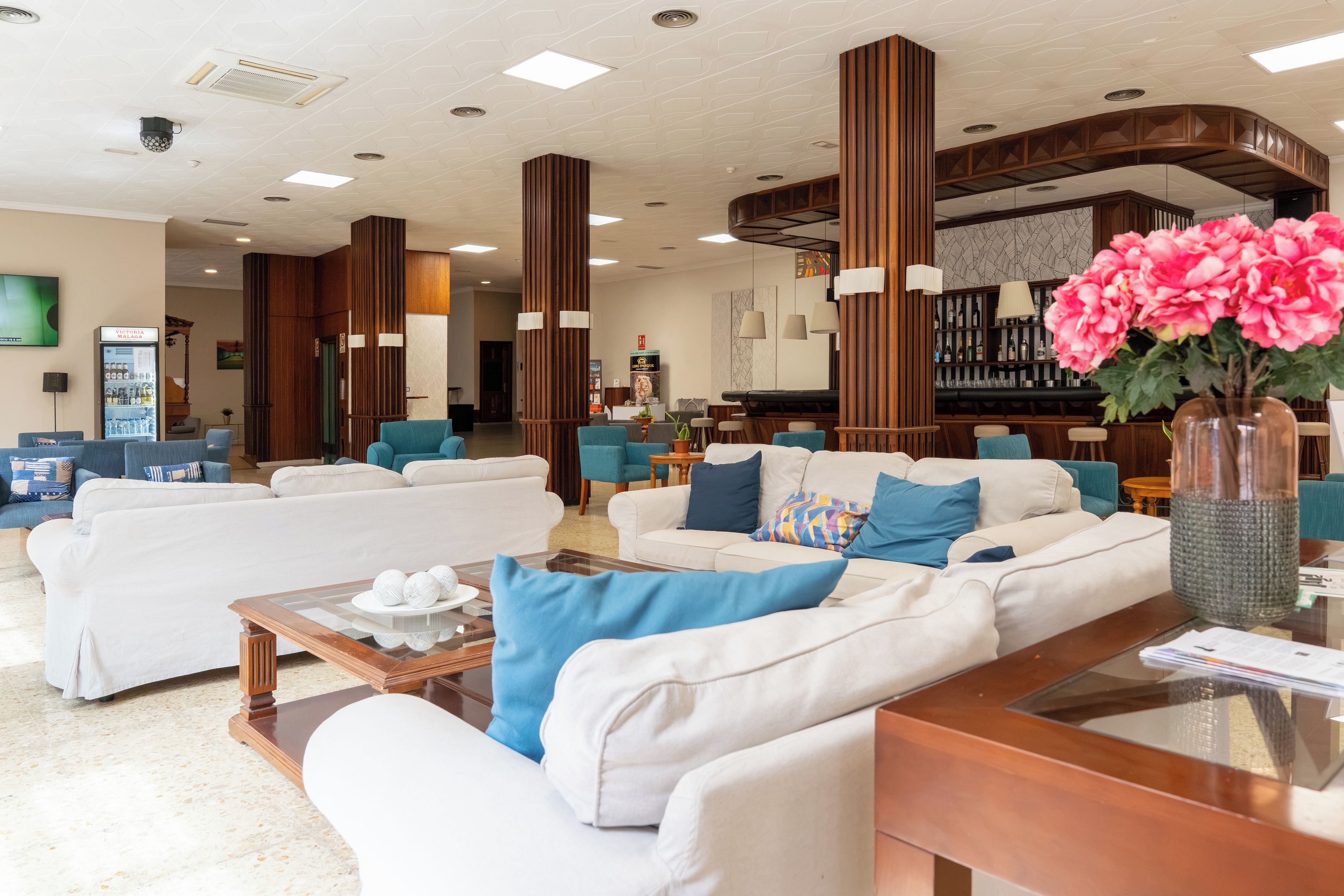 Een moderne hotelentree met een bar, zithoekjes en een automaat voor verfrissingen.
