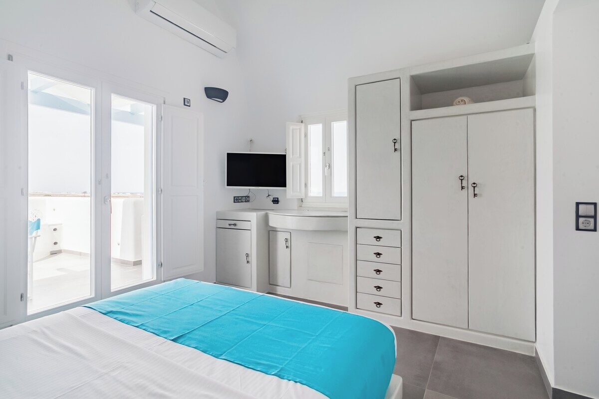 Ein Hotelzimmer mit Bett, Fernseher, Kleiderschrank, Schreibtisch und Bad.