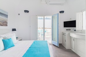 A hotel room with a bed, a TV, a bathroom, and a view of the outside.