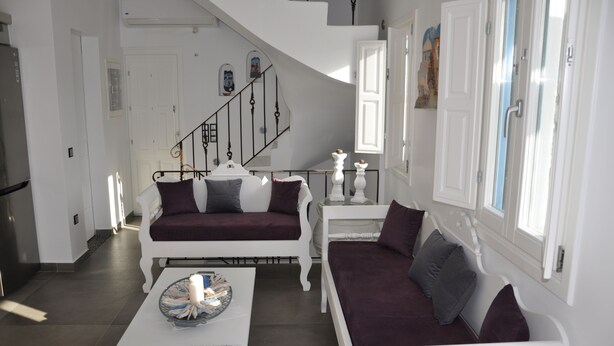 Una sala de estar moderna con una escalera blanca, un conjunto de sofás y una mesa de centro.