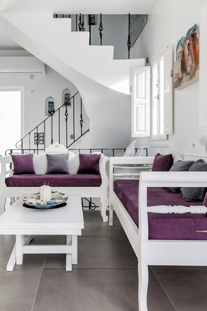 Un interior modern amb una escala blanca, un sofà i una taula de menjador.