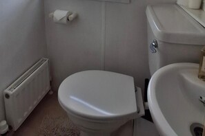 A standard bathroom with a toilet, a radiator, and a sink.