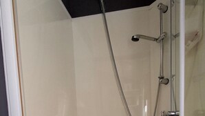 Eine begehbare, gläserne Dusche mit weißem Boden, einer Duschbrause und einem Handbrauseinsatz.