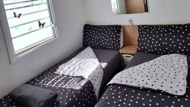 Ein kleines, gemütliches Zimmer mit einem Bett, einem Nachttisch und einem Fenster mit Schmetterlingsaufklebern.