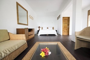 A hotel room with a bed, a sofa, a coffee table with flowers, a dresser, and a mirror.