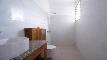 A bathroom with a white sink, wooden cabinet, and a shower.