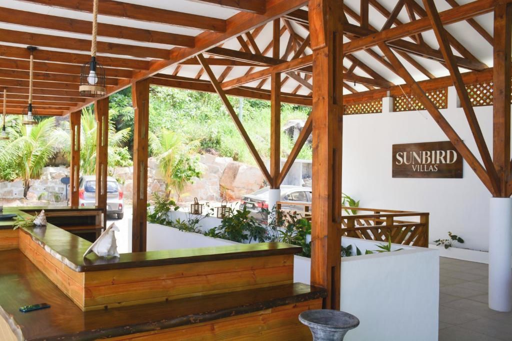 Une structure en bois comprenant un comptoir d’accueil, un bassin en pierre et une enseigne indiquant « SUNBIRD VILLAS ».