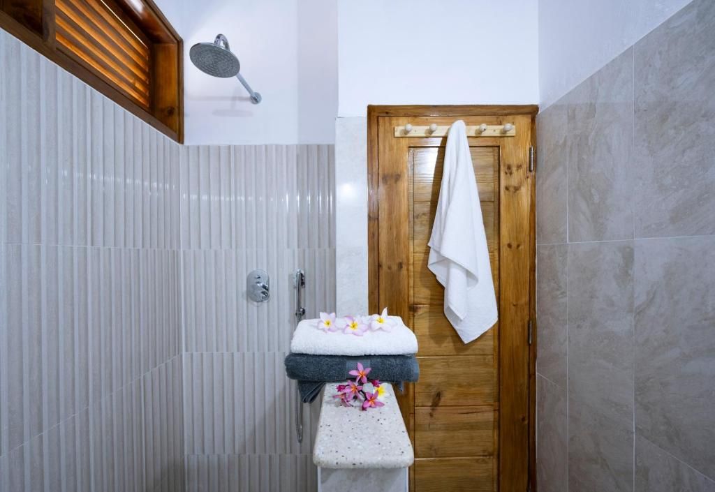 Ein Badezimmer mit Dusche, einer Holztür und einem Handtuchhalter.