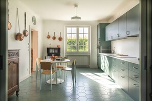 Een moderne keuken met een eethoek, met honingraat tegels, een raam met uitzicht en diverse keukengerei.