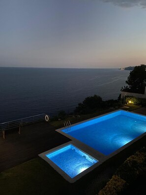 A swimming pool with a view of the sea at dusk. - Exclusive luxurious frontline apartement (Sant feliu de Guixols)