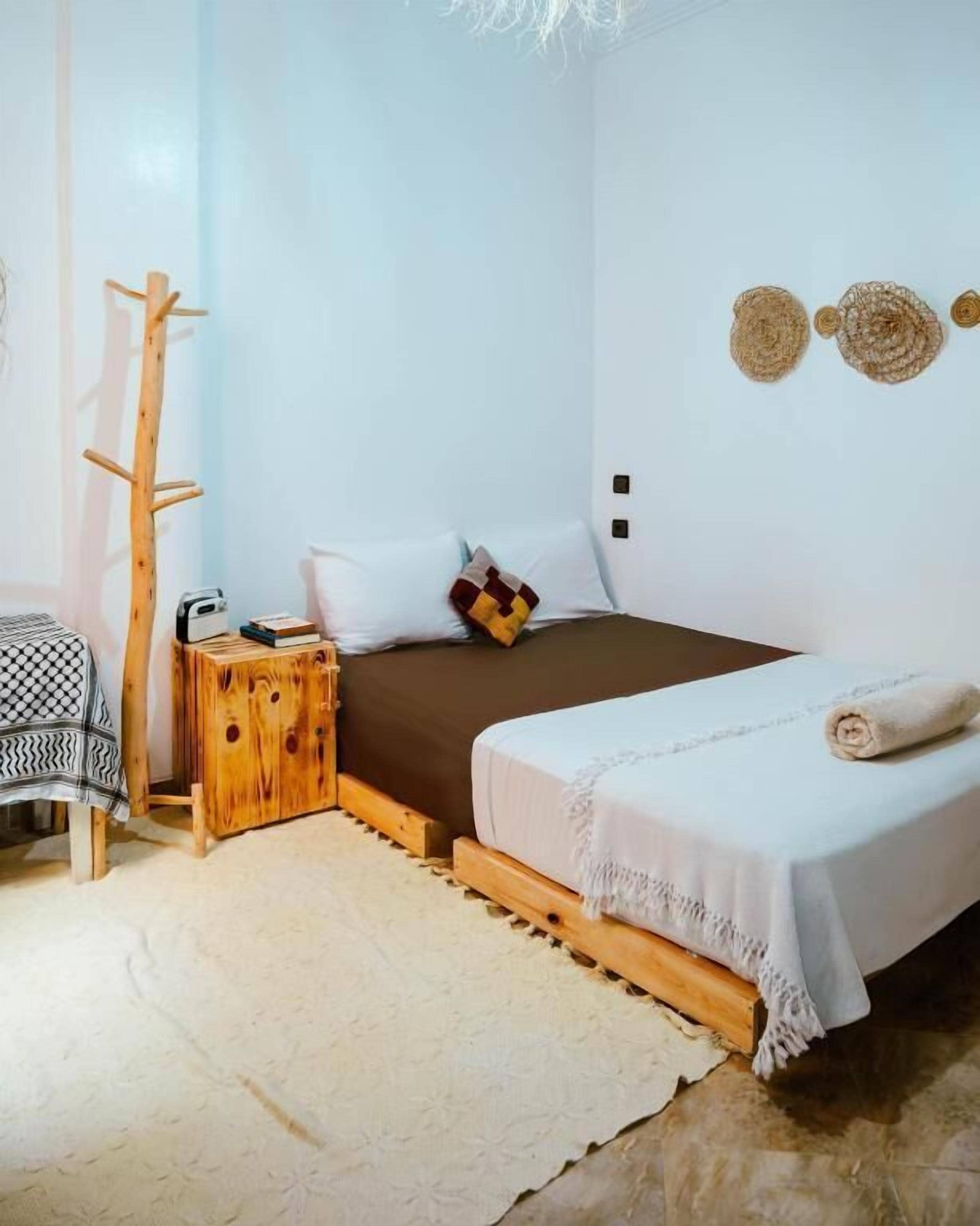 Une chambre à coucher avec un lit, une table de chevet et un porte-manteau en bois.