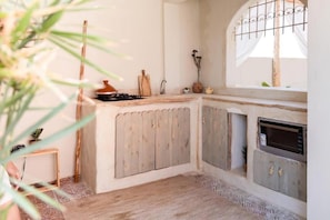 Una cocina rústica con mostrador de madera, estufa y ventana con reja de metal.