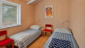 Quarto com duas camas de solteiro, janela com persianas, um pôster na parede e um lustre.