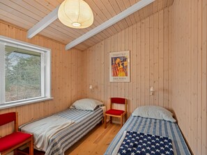 Ein Zimmer mit zwei Einzelbetten, einem Fenster mit Jalousien, einem Poster an der Wand und einer Hängelampe.