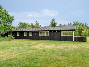 Un bâtiment en métal noir, doté d’un toit plat, de nombreuses fenêtres et d’une zone délimitée par une clôture.