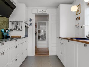Une cuisine moderne avec des meubles blancs, un plan de travail en bois et une vue sur la salle à manger.