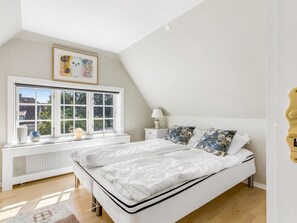 A bedroom with a large bed, a window with multiple panes, a radiator, a nightstand, and a wall-mounted light fixture. - "Annagrete" - 300m from the sea by Interhome (Skagen)