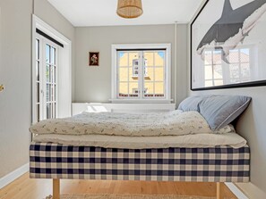 Une chambre à coucher avec un lit, une fenêtre, une porte et un tableau accroché au mur.