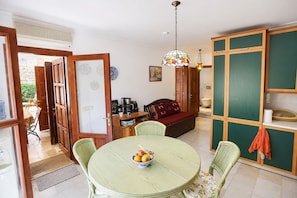 Ein Zimmer mit Esstisch, Stühlen, einer Couch, einer Kaffeestation und einem grünen Schrank.