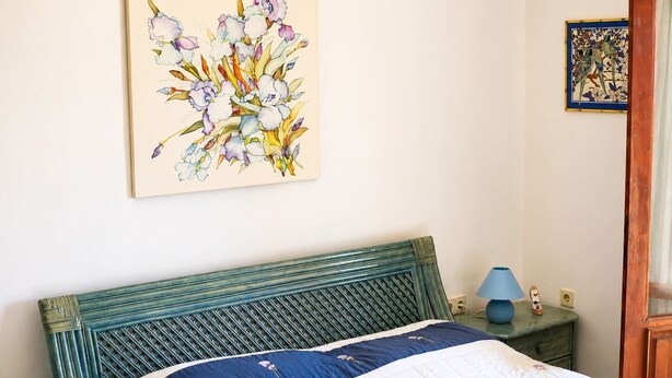 A bedroom with a bed, a headboard, a nightstand, a lamp, and a wall art piece. - Villa Sophia (KAŞ)