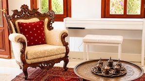 A traditional room with a wooden armchair, a white bench, and a decorative tray with metal items. - Villa Sophia (KAŞ)