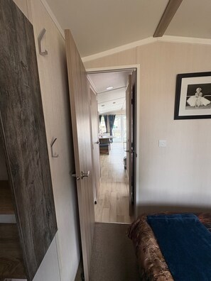 A bedroom with a bed, a wardrobe, and a door leading to a balcony. - Billing Aquadrome 2-bed Caravan, Sleeps 6, Parking (Northampton)