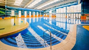 An indoor swimming pool with a tiled floor, a diving board, and a ceiling with skylights. - Billing Aquadrome 2-bed Caravan, Sleeps 6, Parking (Northampton)
