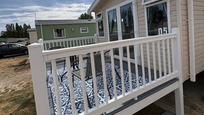 A mobile home with a fenced porch, a satellite dish, and a number '05' on the window. - Billing Aquadrome 2-bed Caravan, Sleeps 6, Parking (Northampton)