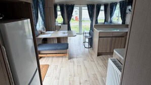 A compact kitchen with a dining area, a bench, and a refrigerator. - Billing Aquadrome 2-bed Caravan, Sleeps 6, Parking (Northampton)
