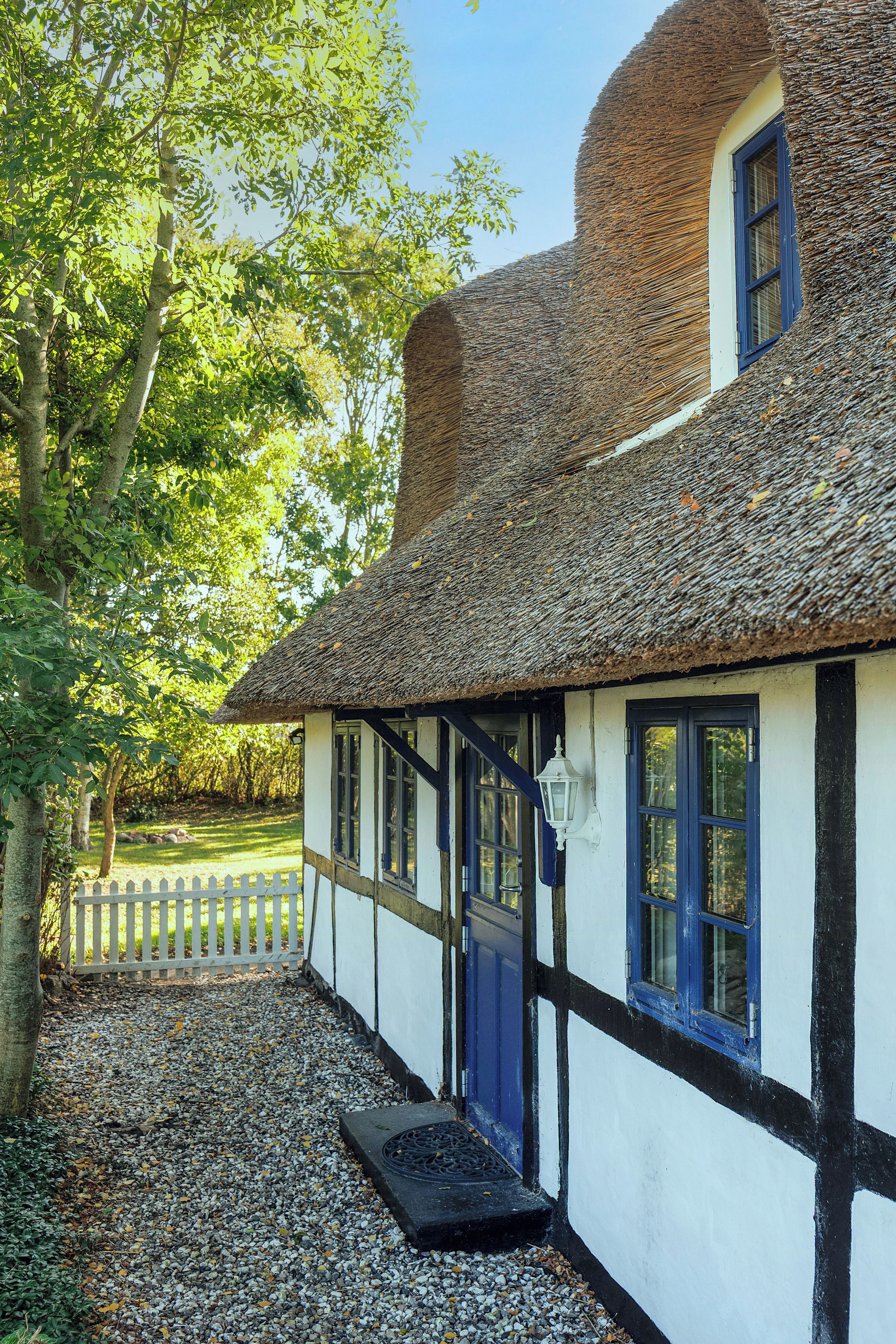 A traditional building with a thatched roof, white walls, and blue trim.