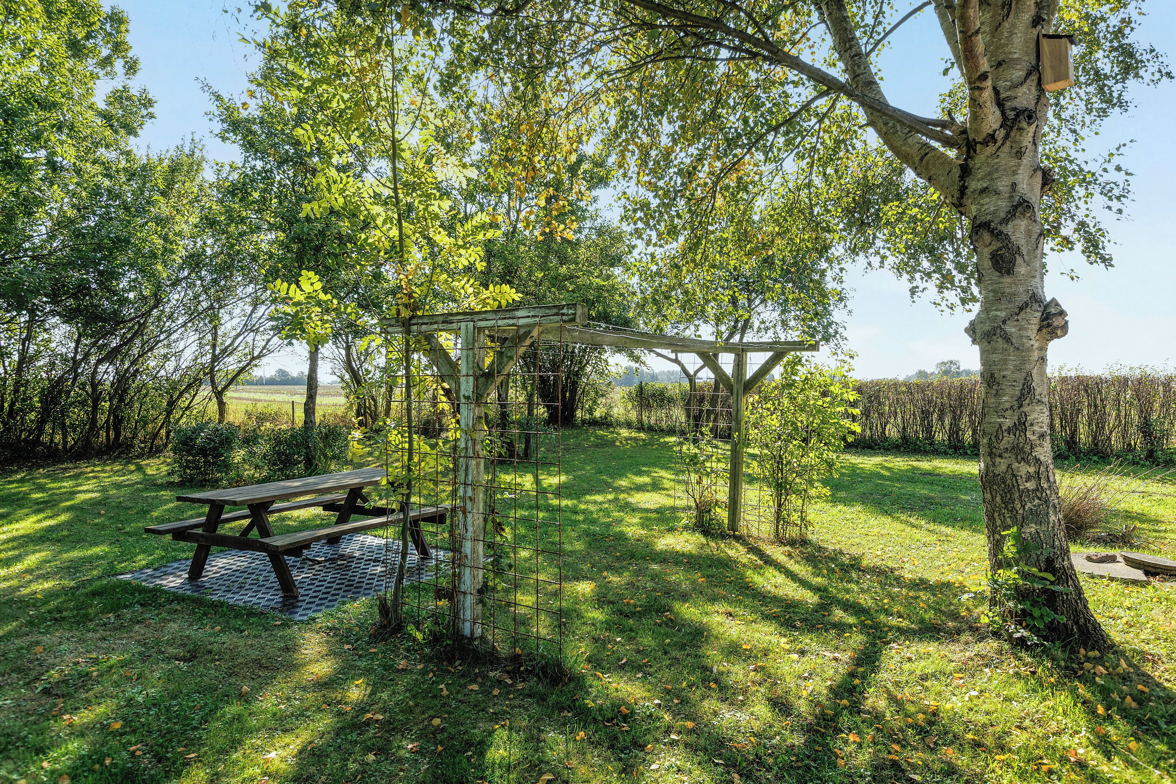 Un área de picnic con un banco de madera y una zona de estar techada.